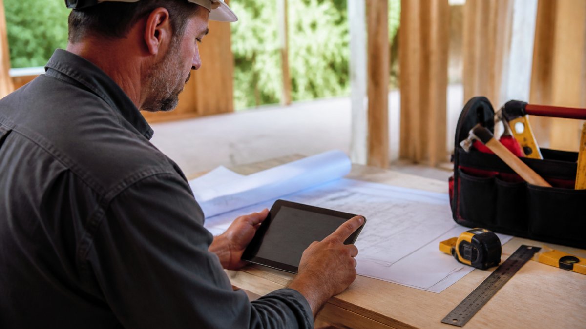 Contractor using a tablet for AI driven lead generation for contractors while reviewing blueprints at a job site